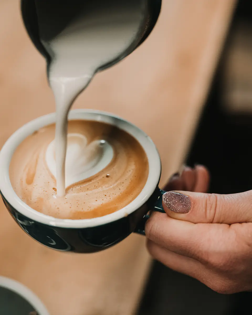 Steamed milk being poured into a cup to form latte art