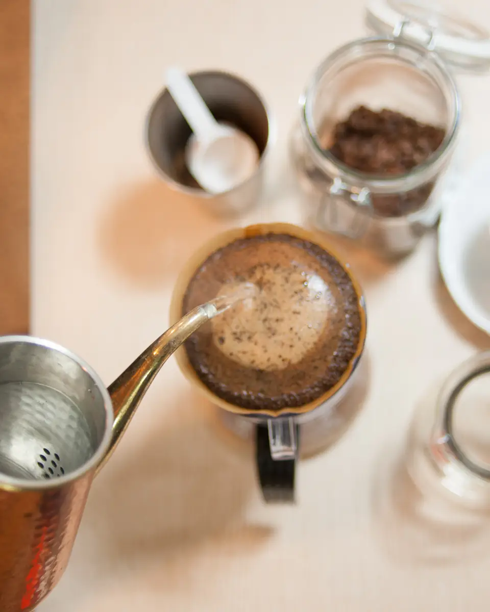 Water poured from a gooseneck kettle into a pour-over dripper, seen from above