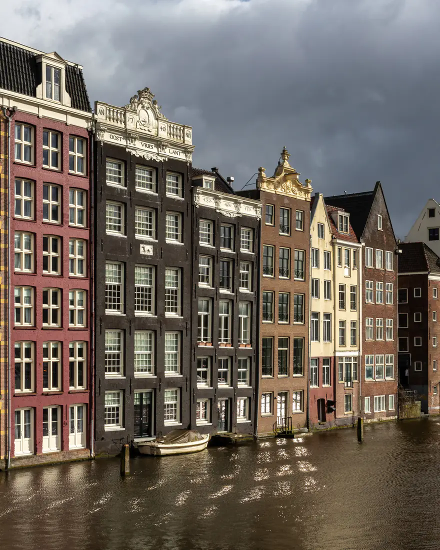 Colorful canal houses along the Damrak in Amsterdam at golden hour