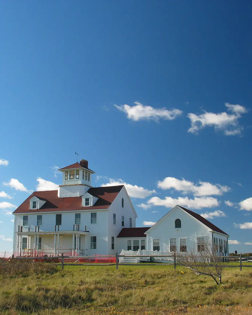 A historic white coastal building on Cape Cod under a blue sky
