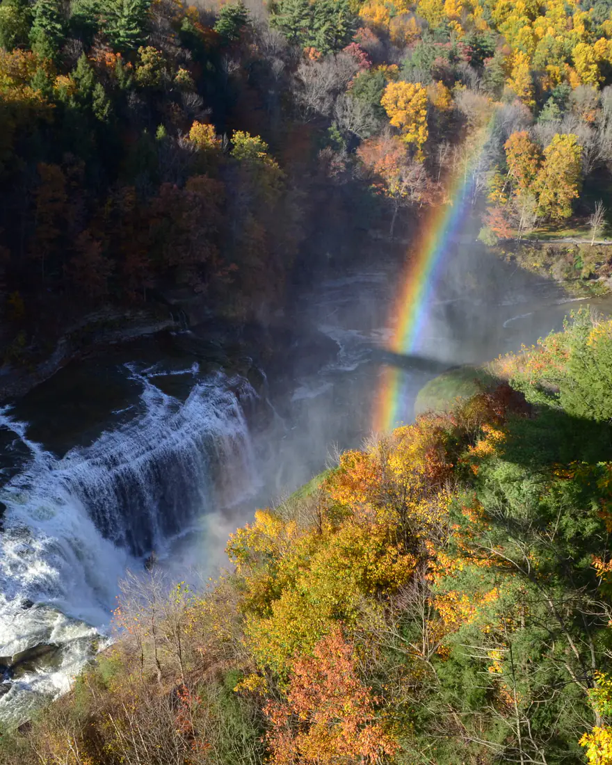 Letchworth State Park's gorge and falls in autumn, with a rainbow in the mist